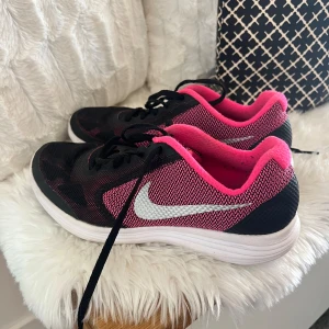 Svarta och rosa Nike sneakers - Säljer ett par snygga och bekväma Nike sneakers i svart och rosa. De har en vit sula och klassisk Nike-logga på sidan. Perfekta för träning eller vardagsbruk. Skorna är i bra skick (passar badet använda inomhus) och redo för nya äventyr!