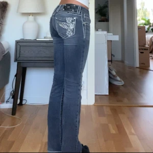 Blå jeans från Miss Me - Säljer ett par snygga blå/svarta jeans från Miss Me i storlek 27💞. De har en bootcut-stil och är lågmidjade. Jeansen har coola broderade detaljer på bakfickorna i form av kors.💞ända defekten är ett pyttelitet hål mellan benen men går att använda hur bra som helst ändå!  skriv om du har några frågor!💞            Midjemått: 37cm                           Innerbenslängd: 73cm