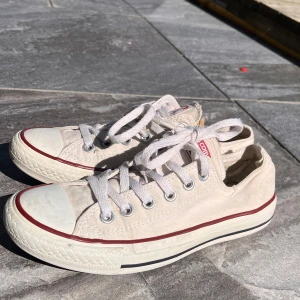 Vita CONVERSE - Vita converse i storlek 37,5 I använt skick med en riven insida på högra skon därav proset. Går ändå super bra att använda och sy ihop eller så.