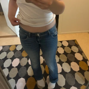 Blå bootcut jeans - Säljer ett par snygga blå bootcut jeans. De är lågmidjade och har en klassisk femficksdesign med knappar och dragkedja. Uppsydda lite grann så de sitter bra på mig som är 162 cm lång💗Perfekta för en avslappnavardagslook!💗