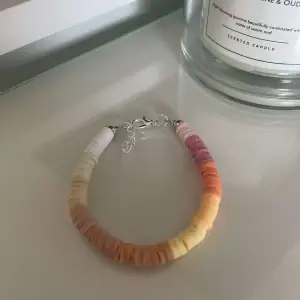 Säljer ett superfint armband med färgglada pärlor i olika nyanser av rosa, orange, gul och vit. Armbandet har en enkel och stilren design med ett smidigt lås. Perfekt för att liva upp vilken outfit som helst!