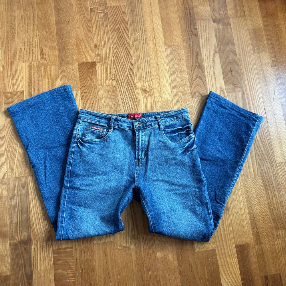 Säljer ett par snygga blå jeans med bootcut-stil. De har coola broderade detaljer på bakfickorna som verkligen sticker ut. Perfekta för en avslappnad look men med en touch av stil. Passar bra till både vardag och fest!. Jeans & Byxor.