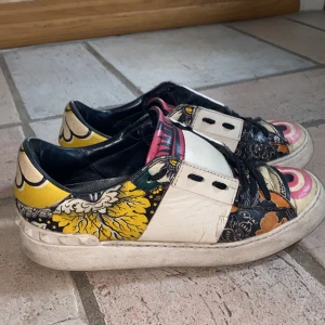 Färgglada sneakers från Valentino - Säljer ett par unika och färgglada sneakers från Valentino. Skorna har ett coolt blommigt mönster i gult, rosa och svart med vita detaljer. Perfekta för att liva upp vilken outfit som helst!😍 
