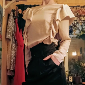 Beige klänning med volangdetaljer - Säljer en superfin beige klänning med volangdetaljer. Perfekt för både vardag och fest! Klänningen har en mjuk och bekväm passform med korta ärmar. Materialet känns lyxigt och faller snyggt.