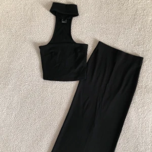 Ginatricot svart set / midikjol och topp med choker - Otroligt snyggt set från Ginatricot med svart midikjol med slits på baksidan och en tillhörande topp med choker. Använt endast i några timmar, i nyskick utan anmärkningar. Storlek XS i båda delar. Formar kroppen fint 🎃
