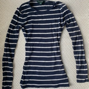 Ralph Lauren tröja - Fin mörkblå och vit randig långärmad tröja från Ralph Lauren. Stretchig och formpassande material, passar även mig som bär storlek S. Har inga defekter eller fläckar men är några år gammal. Minns ej orginalpris🩵