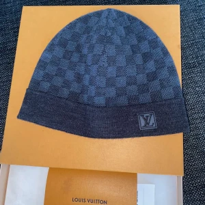 Louis Vuitton mössa  - Louis Vuitton Petit Damier beanie/mössa Inköpt för ett par år sedan på Louis Vuitton affären i Birger Jarlsgatan för 3100 kr. Knappast använd då jag varit så rädd om den, riktigt bra skick finns inget fel  Tar emot förslag för byte 
