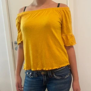 Gul offshoulder topp med volangärmar - Säljer en superfin gul offshoulder topp från Shein. Den har volangdetaljer på ärmarna och är perfekt för sommardagar. Materialet är mjukt och bekvämt, och toppen har en lös passform som gör den luftig och skön att bära. Perfekt för en dag på stan eller en sommarfest! Kontakta för mer information eller vid frågor . Uppskattar storlek S