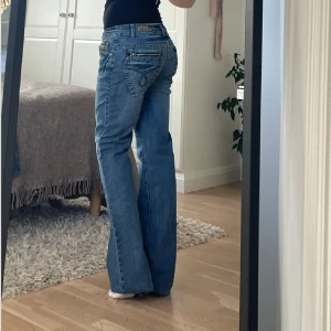 Lågmidjade bootcut jeans - Unika med fina detaljer från Sciapai i storlek S. Miedjemåttet är 41cm tvärs över och innerbenslängden är 85cm. Superfina i bra skick, något nötta längst ned vid benen vilket kan ses på bild. Hör av er vid funderingar🫶