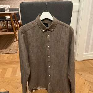 Linneskjorta  - En linne skjorta som aldrig är använd då den var för stor, färjan är lite oklar men typ grå/brun