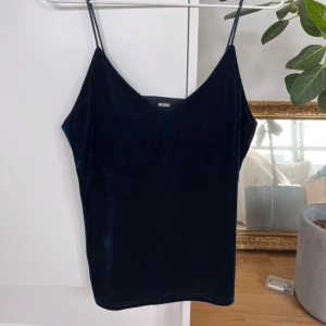Mörkblå sammetstopp från Bik Bok - Säljer en superfin mörkblå sammetstopp från Bik Bok i storlek XS. Toppen har smala axelband och en elegant v-ringning. Perfekt för festliga tillfällen eller en utekväll. Toppen är i mycket bra skick och känns lyxig mot huden. Passar perfekt till både jeans och kjol!