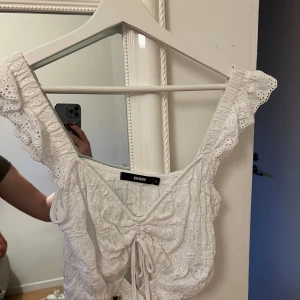 Vit blus från Bik Bok - Säljer en superfin vit blus från Bik Bok i storlek S. Den har söta spetsdetaljer och en knytning framtill. Perfekt för sommardagar eller en festlig kväll. Blusen är i mycket bra skick och har en romantisk stil. 