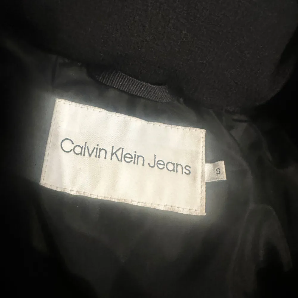 Säljer en snygg svart pufferjacka från Calvin Klein Jeans i storlek S. Jackan har en hög krage och dragkedja framtill. Perfekt för kalla dagar och ger en stilren look. Den är i mycket bra skick och är använd endast en vinter . Jackor.