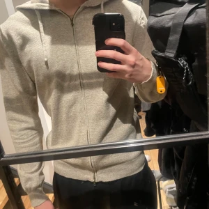Stickad beige full zip hoodie - Säljer en snygg stickad beige hoodie i nyskick då den inte används. Den är från märket the tailoring club. Passar bra på mig som är 185 cm lång. Nypris runt 1500. Vid fler bilder är det bara att skriva.