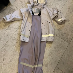 Ljuslila regnställ från MyWear Young - Säljer ett supergulligt ljuslila regnställ från MyWear Young. Jackan har små hjärtan och reflexdetaljer, perfekt för regniga dagar. Byxorna har justerbara hängslen och reflexband vid benen. Perfekt för lek i alla väder! 💜