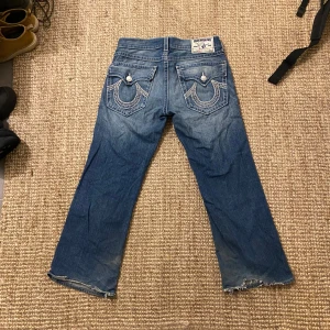 True Religion ”spider web” - Säljer ett par True Religion jeans i blå denim med slitna detaljer och broderade bakfickor. Väldigt unika jeans. Perfekta för en avslappnad stil med lite edge. Passar bra till både vardag och fest! Burna av Chief keef!! 