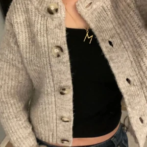 Beige stickad kofta med knappar - Köpt på PLICK (förra säljarens bild) 💕Mysig beige stickad kofta med stora knappar framtill. Perfekt för kyliga dagar och ger en avslappnad look. Koftan är croppad och har en normal passform, vilket gör den lätt att matcha med olika outfits.❤️