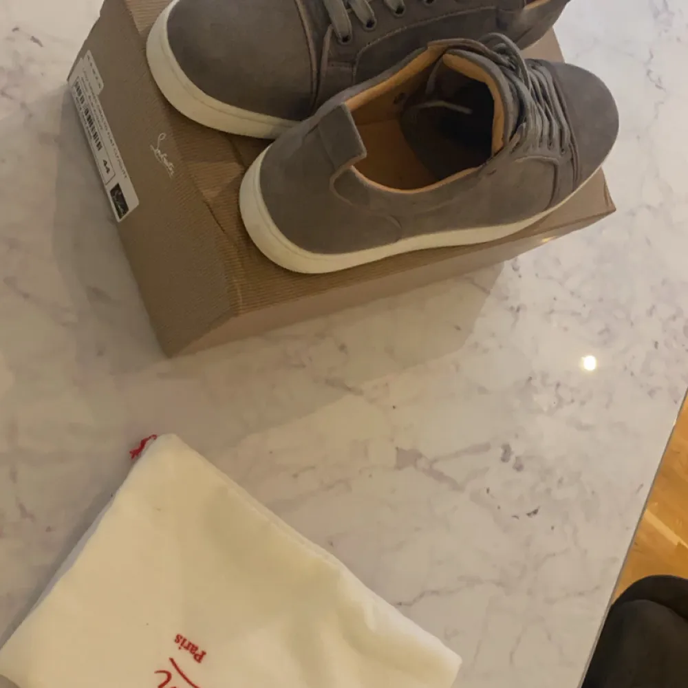 Säljer ett par snygga grå sneakers från Christian Louboutin i mocka. De har den ikoniska röda sulan och snörning framtill. Perfekta för både vardag och fest! Skorna är i mycket bra skick och kommer med originalpåse.. Skor.