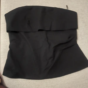 Svart tubtopp med dragkedja - Snygg svart tubtopp perfekt för festliga tillfällen. Den är aldrig använd och prislappen är kvar. Ordinarie pris 329