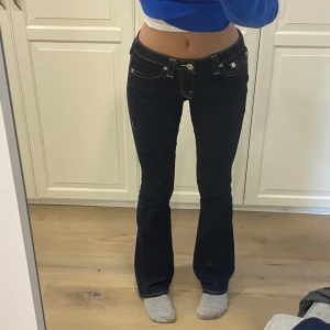 Mörkblåa True Religion Jeans str 27 - Säljer ett par snygga mörkblåa bootcut jeans med vita sömmar från True Religion i modellen Becca. De är midwaist men sitter som lowwaist, iallafall på mig-se bild😊 använda ca 5 ggr. Storlek 27. Nypris 2500. Hör av er vid frågor❤️