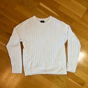 Kabelstickad vit tröja Boomerang - Säljer en snygg vit stickad tröja från Boomerang i storlek M. Den har ett klassiskt flätmönster och är perfekt för året om, men särskillt för skärgården eller västkusten om sommaren. Tröjan är i bra skick och passar till alla tillfällen. Perfekt för att hålla sig varm och stilren! ❄️
