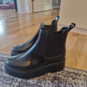Svarta chelsea boots i syntet - Säljer ett par svarta chelsea boots i syntetmaterial. De har en robust sula med bra grepp och elastiska paneler på sidorna för enkel på- och avtagning. Perfekta för regniga dagar och höstpromenader. Använda men i bra skick.