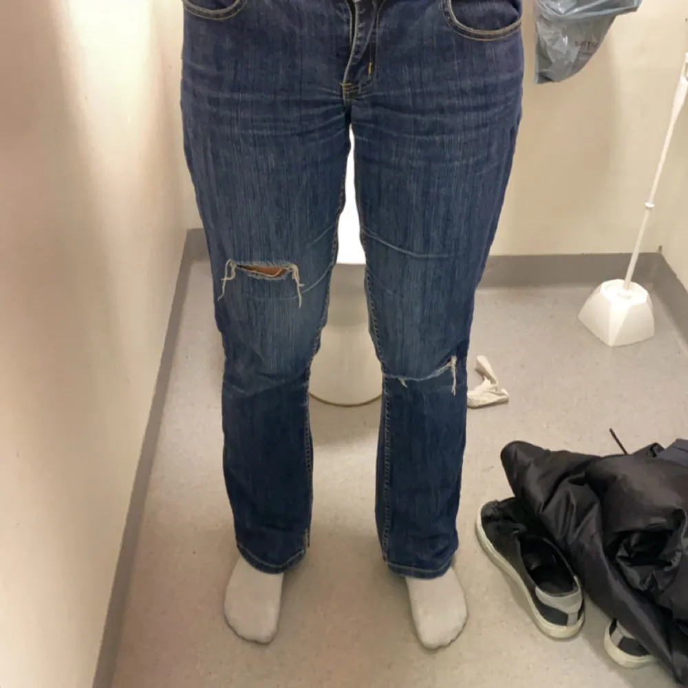 Säljer ett par blå lågmidjade bootcut jeans i bra skick med coola slitningar på knäna. Dom är i väldigt bra skick, ny priset va 799kr. Jeans & Byxor.