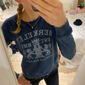 Mörkblå sweatshirt  - Säljer en snygg mörkblå sweatshirt från Berkeley med ett coolt tryck av två lejon och en borg. Tröjan är i bra skick och har en avslappnad passform. Perfekt för höst och vår! 💞