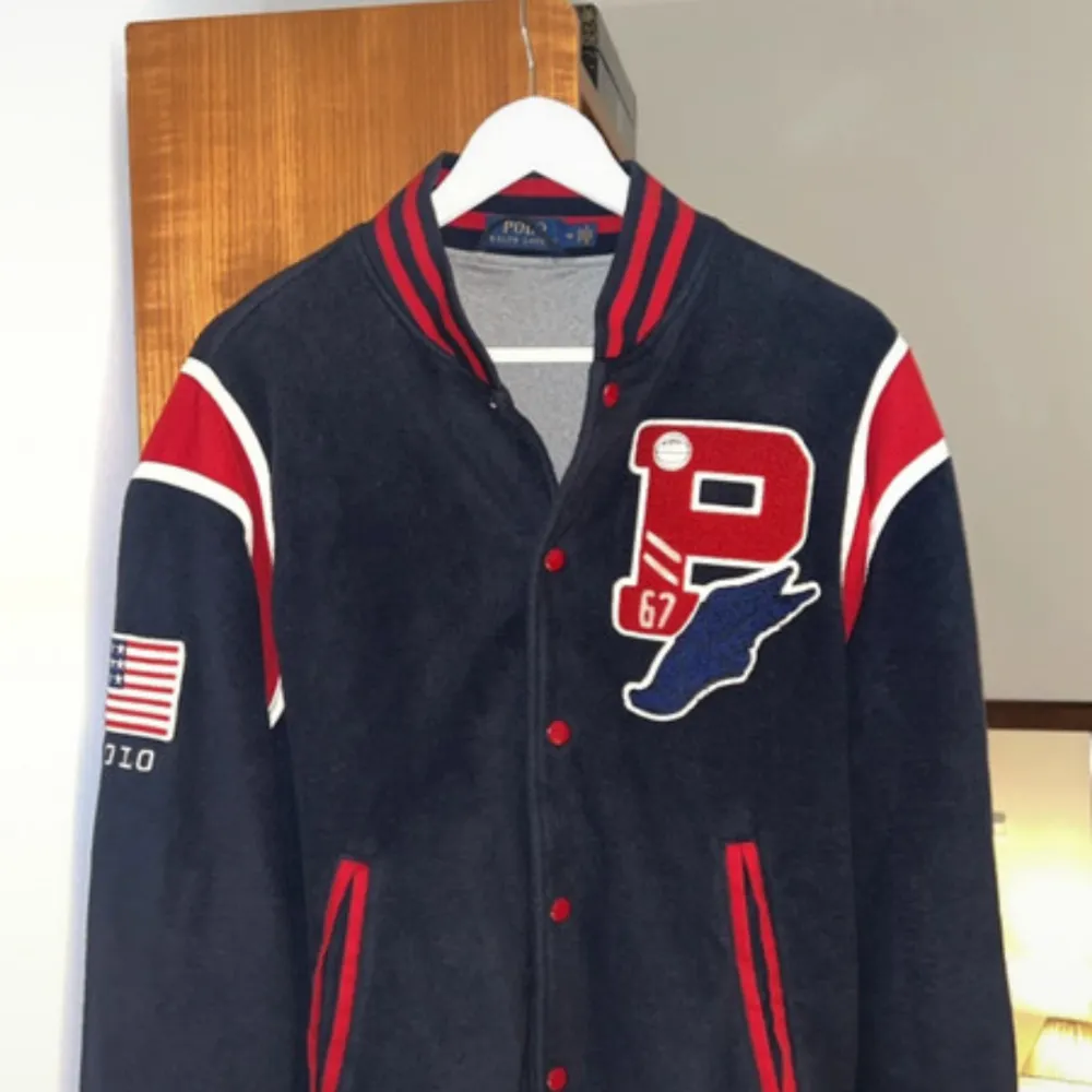 Säljer en snygg blå och röd jacka från Polo Ralph Lauren i storlek M. Jackan har långa ärmar och coola detaljer som USA-tryck på ryggen och ett stort märke på framsidan. Perfekt för höst och vår! 🧥🇺🇸 använd 2-3 gånger . Jackor.