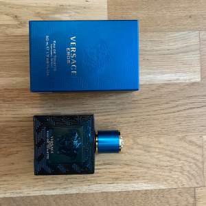 Säljer en Versace Eros Eau de Toilette, 50 ml. Flaskan och förpackningen är i nytt skick. Den är nästan oanvänd, har bara sprejat några få gånger. Flaskan är stilren och turkos med ett elegant mönster och guldiga detaljer. Doften har en mix av vanilj, aromatiska och gröna noter, med inslag av fräsch krydda och citrus. Perfekt för den som vill ha en fräsch och träig doft med en söt touch. Fri leverans ingår!