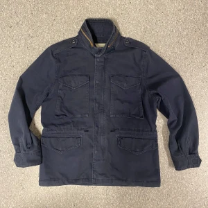 Blå fieldjacket Ralph lauren - Säljer en snygg mörkblå jacka från Denim & Supply Ralph Lauren. Jackan har en klassisk design med fyra fickor framtill och knappar vid kragen. Perfekt för höst och vår, tillverkad i bomull för en bekväm passform. Passar både till vardags och lite finare tillfällen. Passar lite större