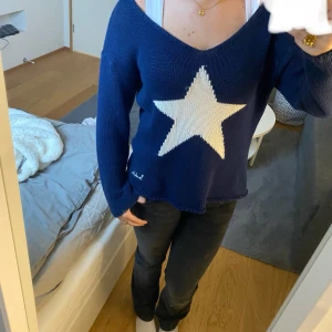 Mörkblå stickad tröja med stjärna från Bondelid - Säljer en superfin mörkblå stickad tröja från Bondelid med en stor vit stjärna på framsidan. Tröjan har en v-ringad hals och långa ärmar, perfekt för höst och vinter. Den är i bra skick och passar perfekt för en avslappnad stil. Exklusive frakt.