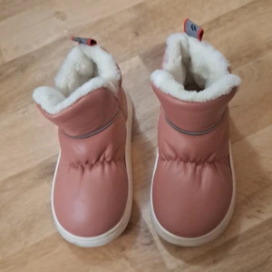 Rosa vinterboots med foder - Superfina rosa vinterboots i syntetmaterial med fluffigt vitt foder. Perfekta för kalla dagar med sin mysiga insida. De har en enkel design utan snörning, vilket gör dem lätta att ta på och av. Sulan är vit och har texten 'fashion' på sidan. Perfekta för vinterns alla äventyr! 36-37 står på det ❄️