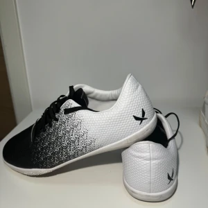 Svartvita sneakers med snörning - Säljer ett par stilrena svartvita sneakers i syntetmaterial. Skorna har en cool gradientdesign från svart till vitt och är perfekta för både vardag och träning. De har snörning för en bra passform och en bekväm sula för långa promenader. Perfekta för dig som vill ha en sportig look!