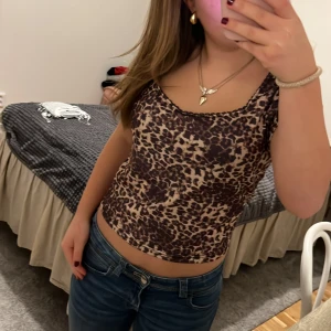 Leopardmönstrad linne - Säljer ett snyggt leopardmönstrat linne i bruna och beige toner. Perfekt för en utekväll eller sommarens fester. Linnet har en tight passform och ärmlös design som ger en trendig look. Matcha med jeans eller kjol för en komplett outfit!