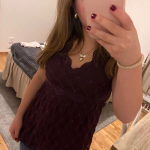 Mörklila spetslinne - Säljer ett superfint mörklila spetslinne med v-ringning. Perfekt för en utekväll eller fest! Det har en romantisk känsla med spetsdetaljer och en smickrande passform. Passar perfekt till jeans eller kjol. Storlek är inte angiven men ser ut att vara en mindre storlek.