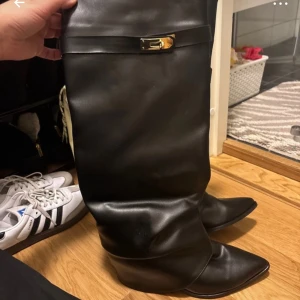 Svarta stövlar med gulddetalj - Snygga svarta stövlar i skinn med en elegant gulddetalj på sidan. De har en spetsig tå och en låg klack, vilket gör dem både stiliga och bekväma. Perfekta för höst och vinter, och passar bra till både vardag och fest. Skorna är i mycket bra skick och redo för nya äventyr!