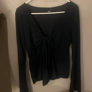Mörkblå tröja från Gina Tricot - Snygg marinblå långärmad topp från Gina Tricot med en unik knytdetalj framtill. Perfekt för både vardag och fest. Materialet är mjukt och stretchigt vilket ger en bekväm passform. Storlek M men passar S. Aldrig använd.