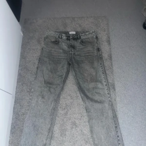 Grå jeans från ASOS DESIGN - Säljer ett par grå jeans från ASOS DESIGN i bra skick. De har en klassisk femficksdesign och är tillverkade i ett slitstarkt denimtyg. Perfekta för vardagsbruk och kan enkelt matchas med olika outfits.