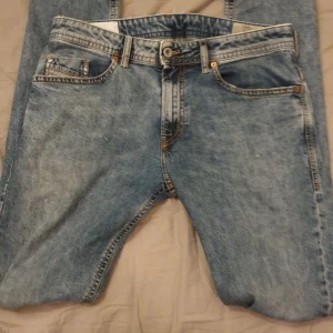 Blå jeans från Diesel - Säljer ett par snygga blå Diesel Thommer jeans i slim-skinny passform. De har en klassisk femficksdesign med slitna detaljer på bakfickorna för en cool look. Perfekta för både vardag och fest! 🕺