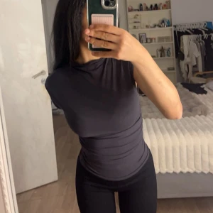 Svart tight topp - Säljer en svart tight topp i mycket bra skick. Den är ärmlös och perfekt för både vardag och träning. Materialet är stretchigt och bekvämt, vilket gör den idealisk för en aktiv livsstil.