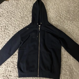 Hoodie från Pier One - Säljer en stilren svart hoodie från Pier One i bra skick. Den har en dragkedja framtill och en praktisk huva med snörning. Perfekt för både höst och vår, och passar till de flesta outfits. Materialet är en blandning av bomull och polyester vilket gör den både bekväm och hållbar. Aldrig använd. Storlek S men är ganska stor