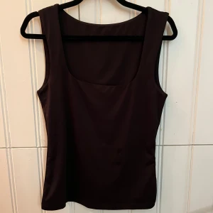 Svart ärmlös topp från Vero Moda - Snygg svart ärmlös topp från Vero Moda i storlek XS. Perfekt för både vardag och fest. Den har en enkel och stilren design som gör den lätt att matcha med olika outfits. Materialet känns mjukt och bekvämt mot huden.