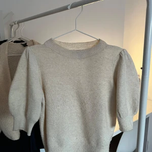 Stickad topp - Säljer denna superfina beiga stickare toppen från Vero Moda med puffiga ärmar. T-shirten är i ett väldigt bra skick då den tyvärr inte kommit till användning särskilt mycket. 