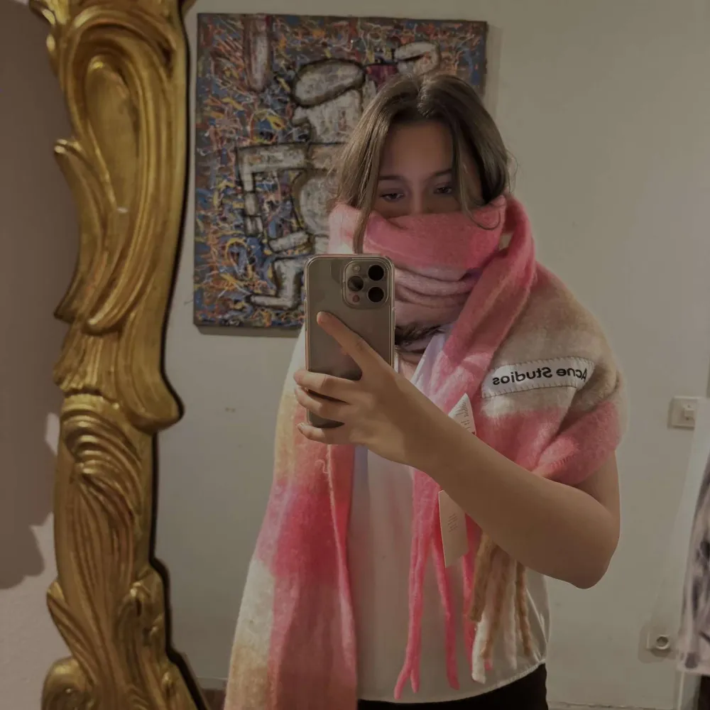 Säljer en superfin rutig halsduk från Acne Studios i rosa, beige och bruna toner. Den är i mycket bra skick aldrig använts och perfekt för att hålla dig varm under höst och vinter. Halsduken är gjord i ett mjukt material och har fransar i ändarna. En stilren accessoar som lyfter vilken outfit som helst!. Accessoarer.