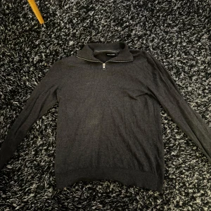 Half Zip  Jack & Jones - Säljer en stilren mörkgrå tröja från Jack & Jones i storlek S. Tröjan har en dragkedja vid halsen och är perfekt för både höst och vinter. Den är i bra skick och passar till många olika outfits. Knappt använd.