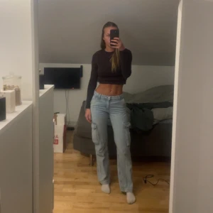 Ljusblå cargobyxor - Säljer ett par ljusblå cargobyxor från ginatricot. De är midwaist och har en rak passform. Storlek 32 men skulle säga att de är mer som en 34a