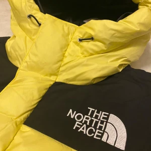 Gul och svart dunjacka från The North Face - Säljer en supercool gul och svart dunjacka från The North Face. Den är i nytt skick med etikett kvar. Jackan har en dragkedja och är perfekt för kalla vinterdagar. Den har en stor huva och är långärmad för extra värme. Perfekt för dig som vill sticka ut i vinter! 💛🖤.                  Nypris 4000kr! 