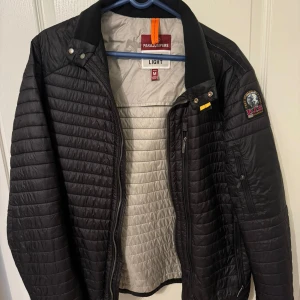 Svart quiltad jacka från Parajumpers - Säljer en snygg svart quiltad jacka från Parajumpers i storlek M. Jackan har en dragkedja framtill och en cool patch på ärmen. Perfekt för höst och vår, med en lätt och bekväm passform. Den är i mycket bra skick och redo för nya äventyr!