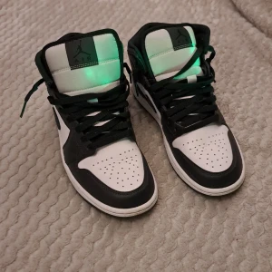 Nike Air Jordans i svart och vit - Säljer ett par snygga Nike Air Jordans i svart och vit. Skorna har en klassisk design med snörning och en cool mönstrad detalj på hälen. De är i mycket bra skick och redo för nya äventyr. 💯💯🤙Säljer dem för 800 nya kostar dem 1500kr. 